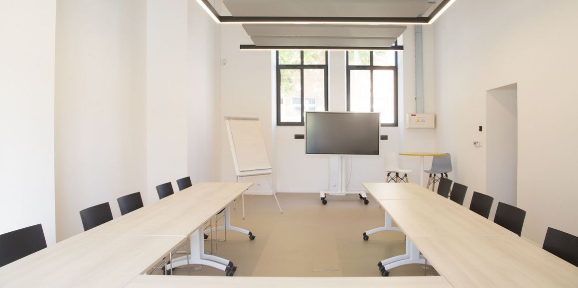 La salle de conférence avec une disposition des tables en U avec un tableau interactif grand format (Flip board)